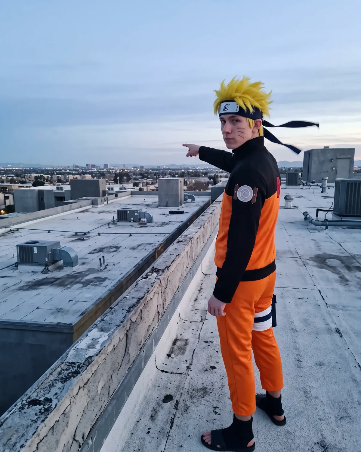 Naruto IRL on a rooftop at dawn, pointing at the city skyline