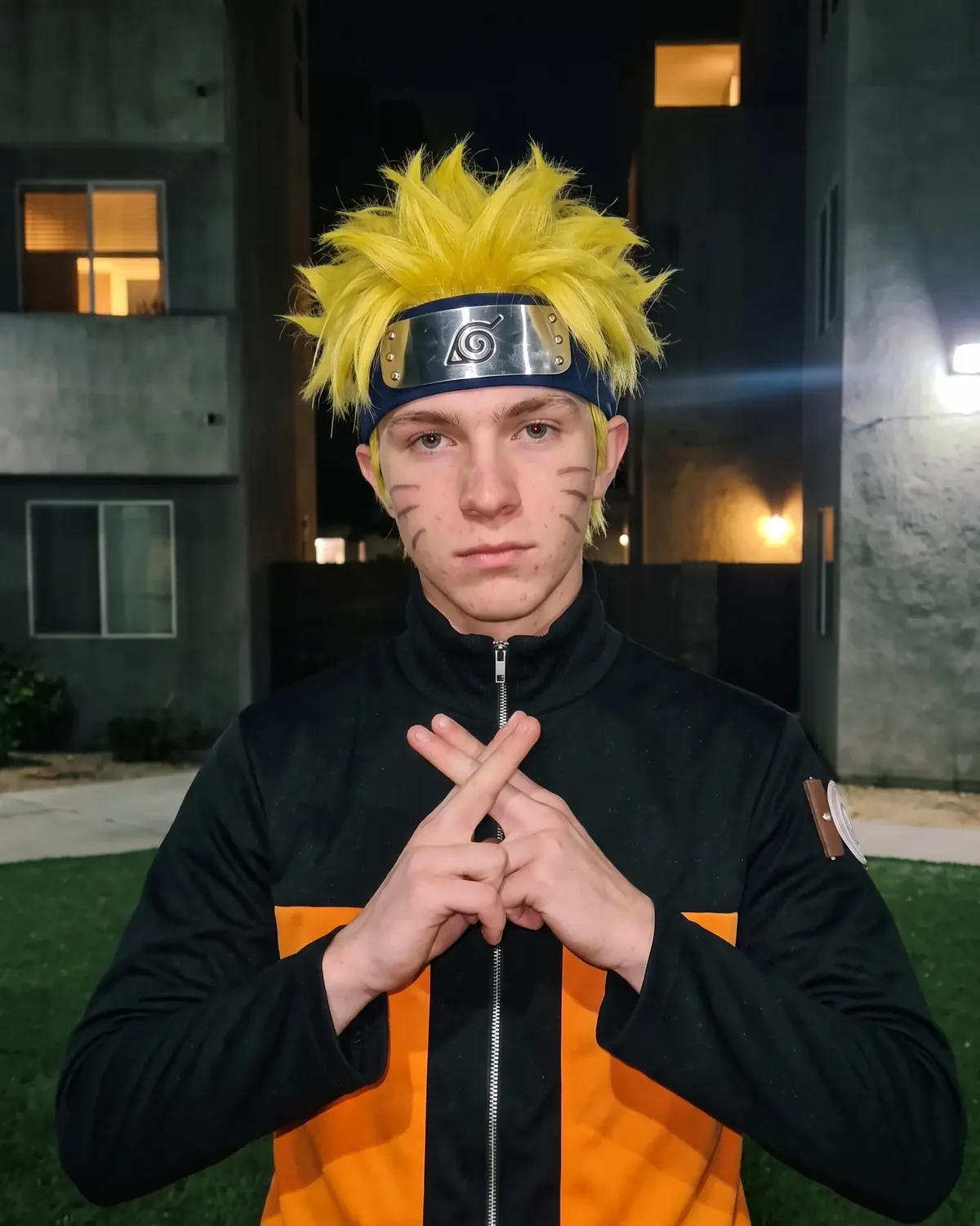Naruto IRL staring at the camera with his index and middle fingers crossed in front of his chest